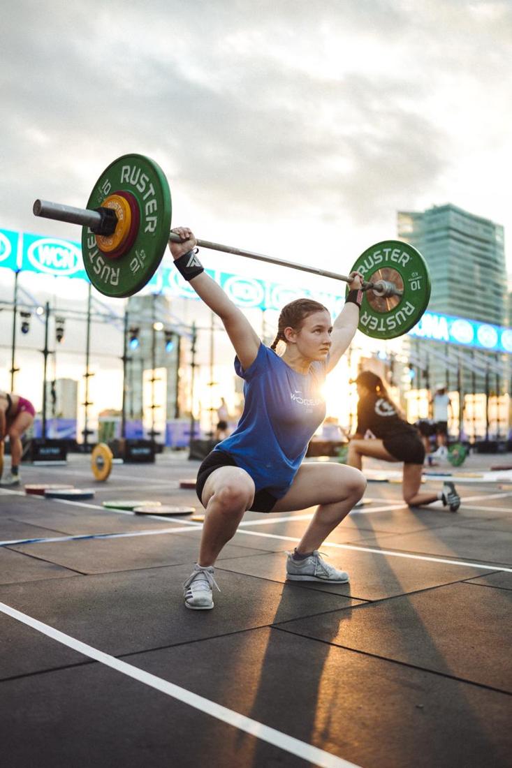 Atleta levantando la barra sobre la cabeza al atardecer