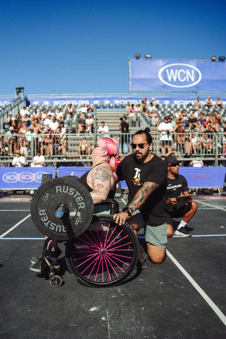 Atleta adaptado en silla de ruedas con un disco, junto a su juez